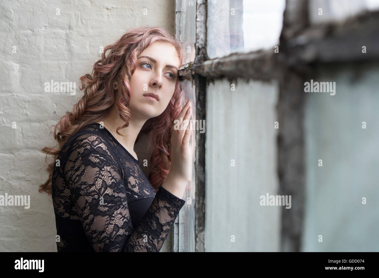 Sad woman standing by the window Stock Photo