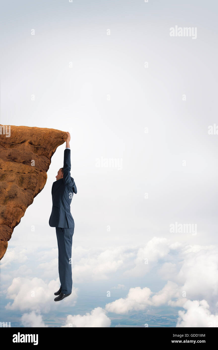 business challenge concept businessman clinging on to a cliff Stock Photo