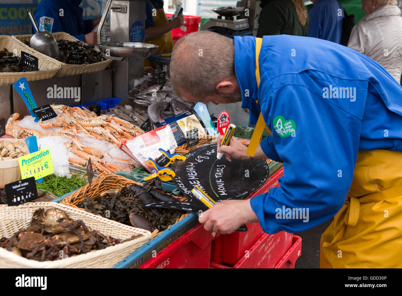 Ireland, Co Galway, Galway, Saturday market, fishmonger writing monkfish tail prices on board Stock Photo