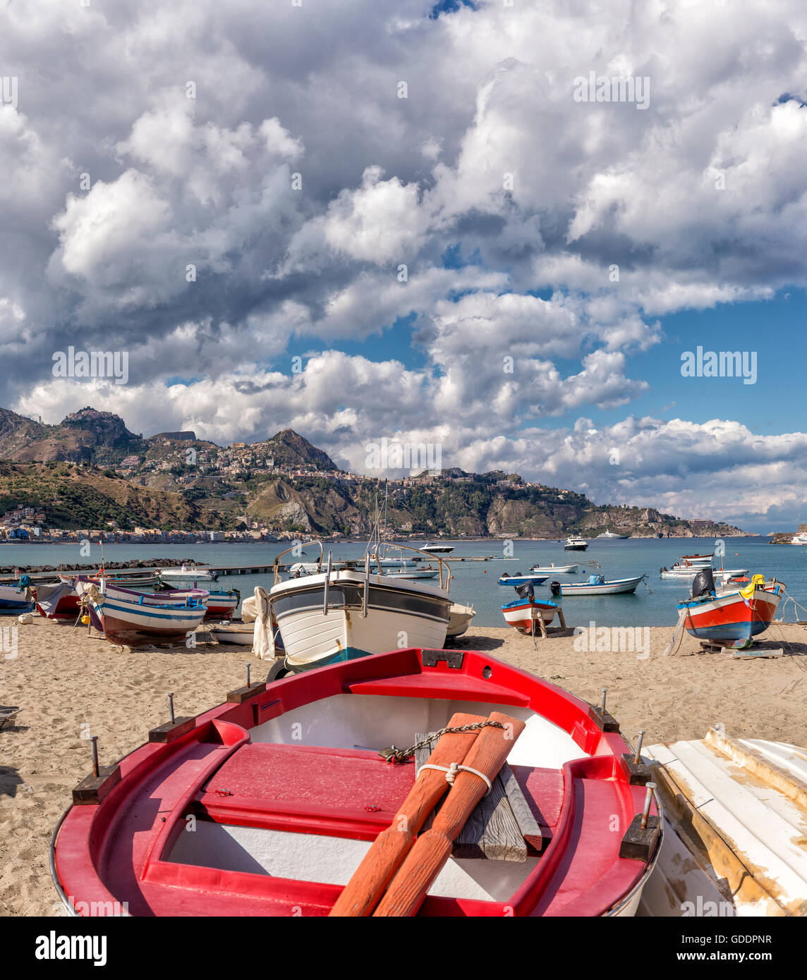 Fishing-boats at the beach,view towards Taormina on a mountain ridge Stock Photo