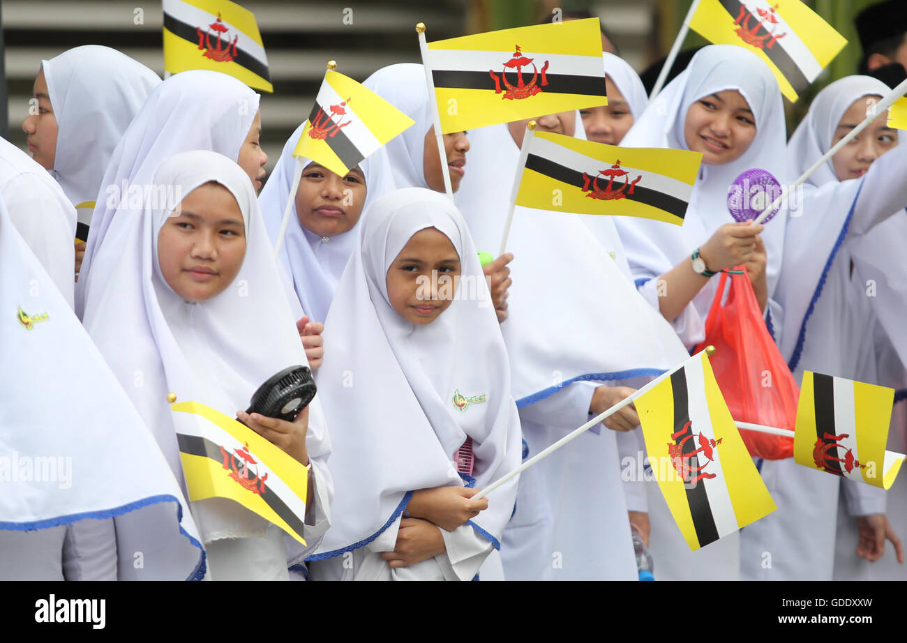 Bandar Seri Begawan, Brunei. 15th July, 2016. People wave national flags to show respect to Brunei's Sultan Haji Hassanal Bolkiah during a ceremony to celebrate his 70th birthday in Bandar Seri Begawan, Brunei, July 15, 2016. Brunei celebrated the Sultan Hassanal Bolkiah's 70th birthday in Bandar Seri Begawan on Friday. The Sultan inspected the honor guard at Omar Ali Saifuddien square and conferred state decorations on 22 people during his 70th birthday investiture ceremony at Istana Nurul Iman palace. Credit:  Jeffrey Wong/Xinhua/Alamy Live News Stock Photo