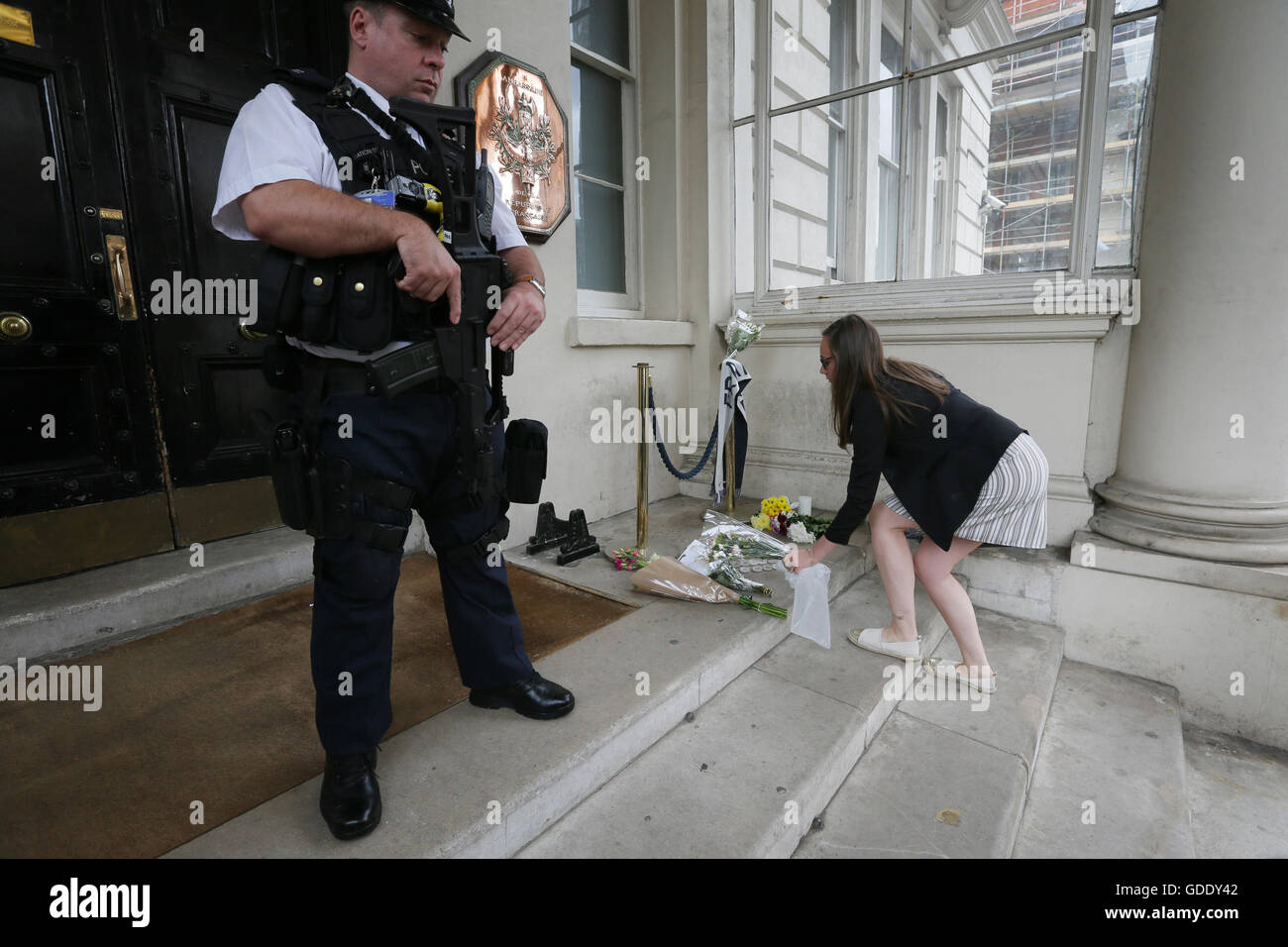 London, London, UK. 15th July, 2016. A woman places flowers outside the French embassy to mourn victims of an attack in which a lorry drove through packed crowds gathered for Bastille Day celebrations in the French city Nice, killing at least 84 people, in London, Britain on July 15, 2016. © Tim Ireland/Xinhua/Alamy Live News Stock Photo