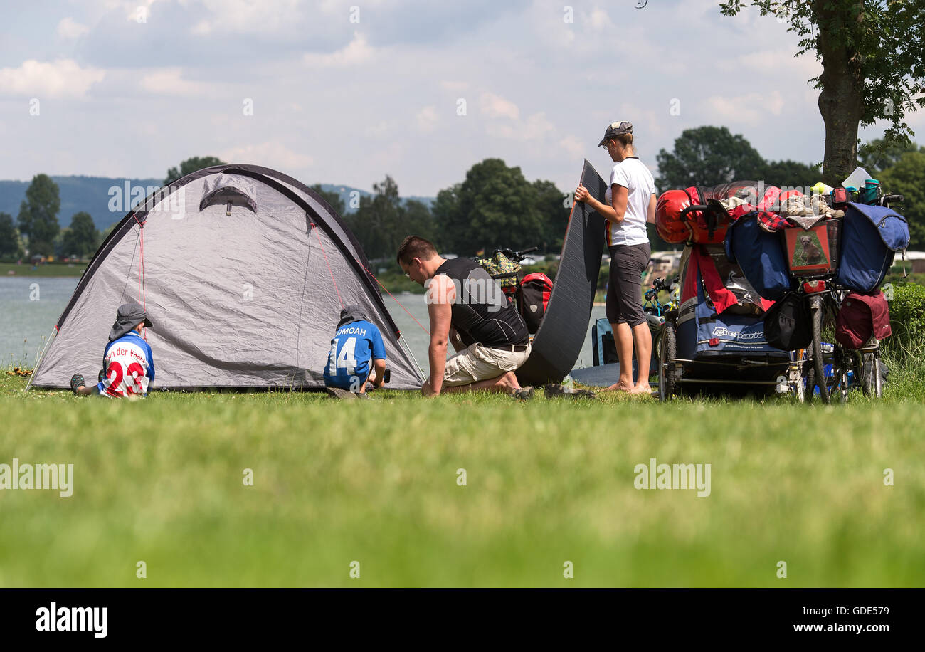 A family set up their tent at the camping site Doktorsee near Rinteln, Germany, 12 July 2016. Photo: Sebastian Gollnow/dpa Stock Photo