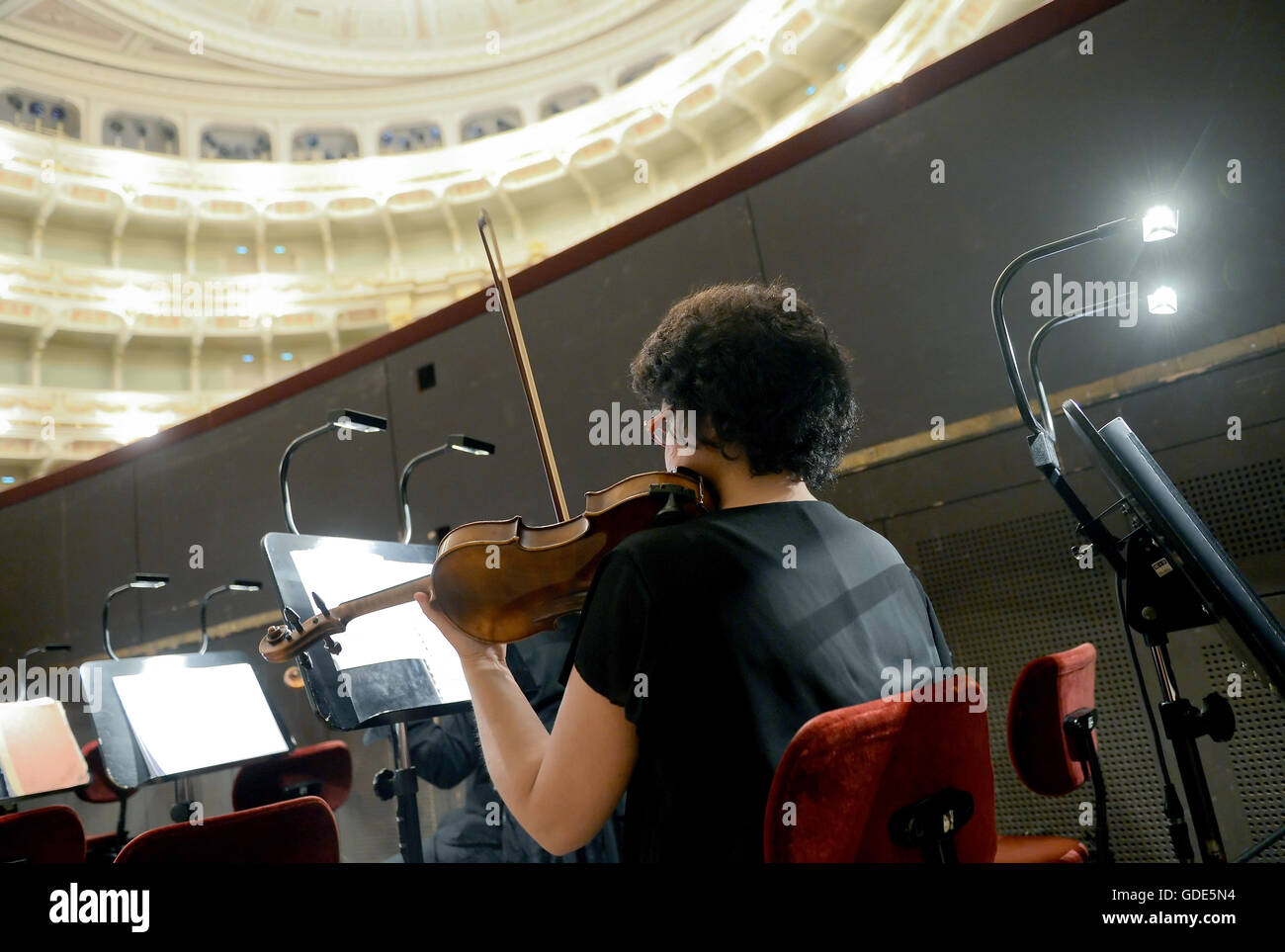 A violinist from the orchestra tuning up during preparations for the
