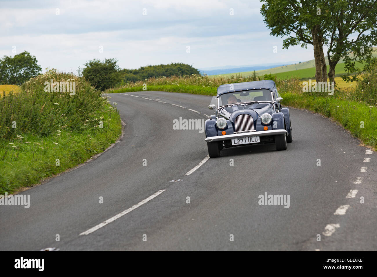 Old car drives through the Dorset countryside on a glorious warm