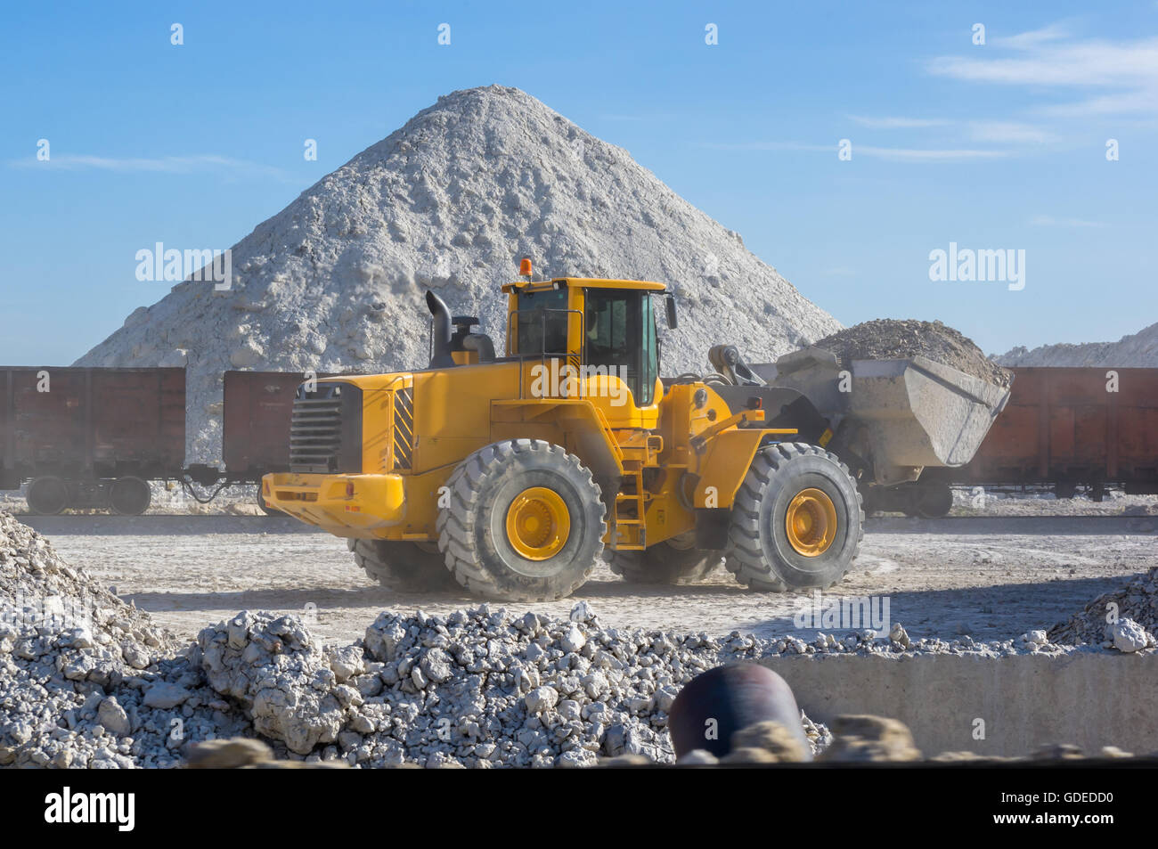 bucket loader loads the unique blue clay in railway cars Stock Photo