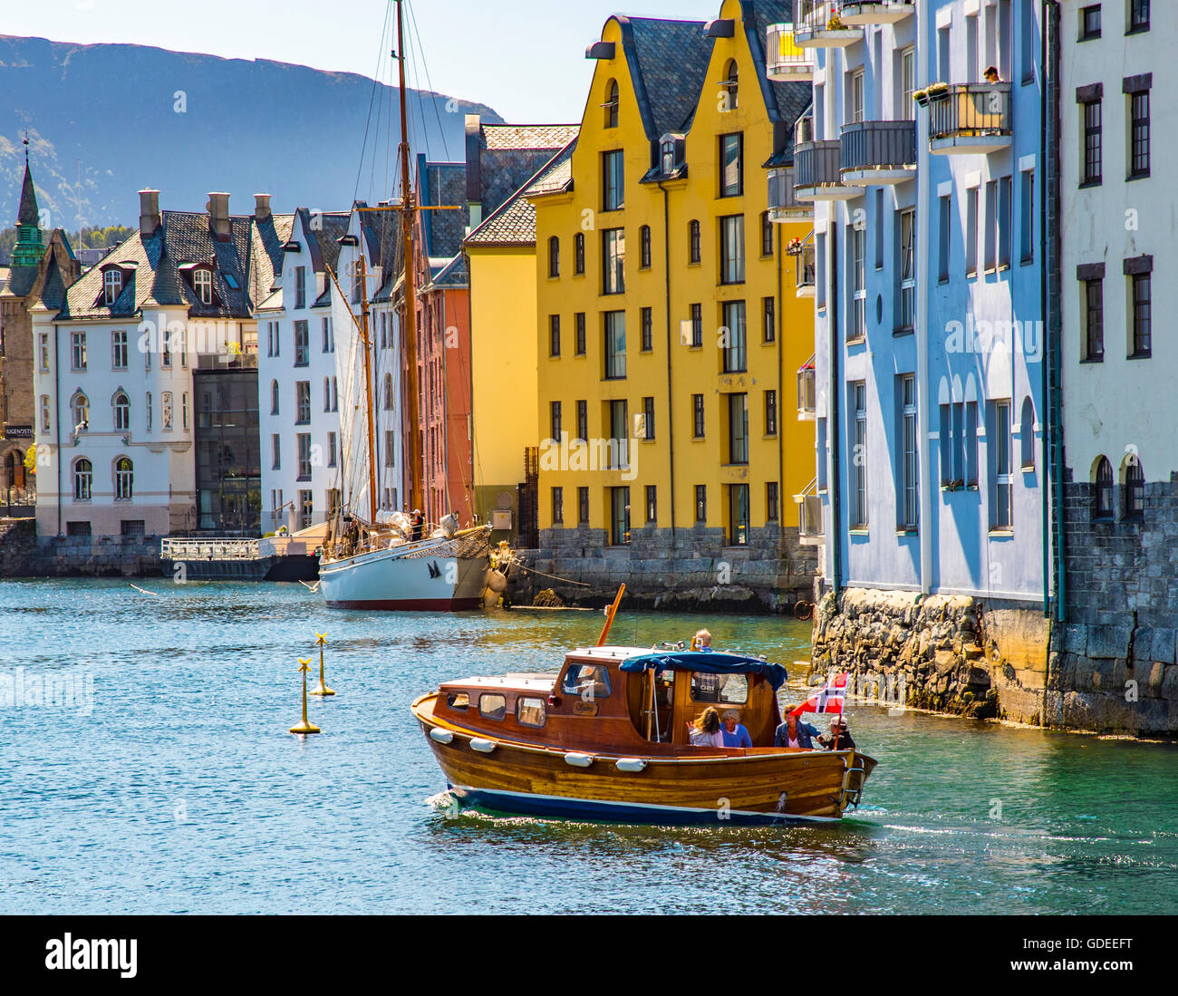 Old wooden boat cruising Brosundet Canal with Art Noveau homes and Hotels. Alesund, Norway, More og Romsdal, Scandinavia, Europe Stock Photo