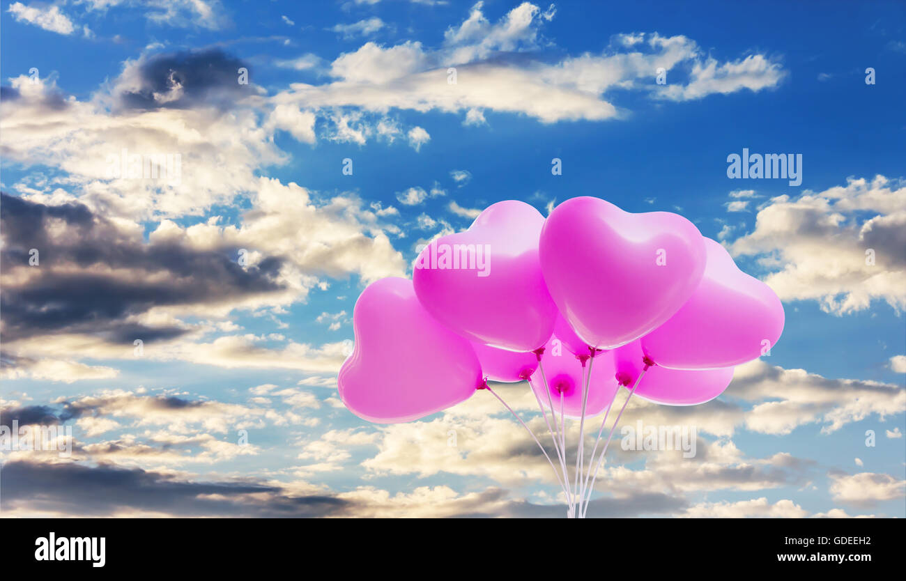 Group of lovely pink heart pattern balloons on puffy cloudy blue sky ...