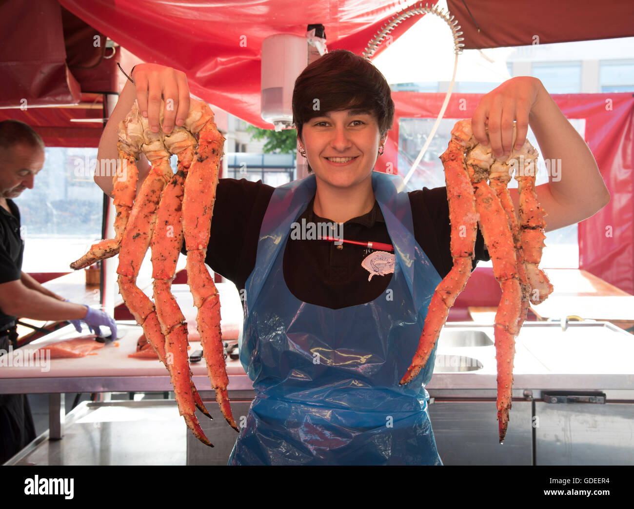Fish seller holding up fresh Crab Legs and shrimp from Sea. Famous Bergen Fish Market, Bergen, Norway, Hordaland, Scandinavia Stock Photo