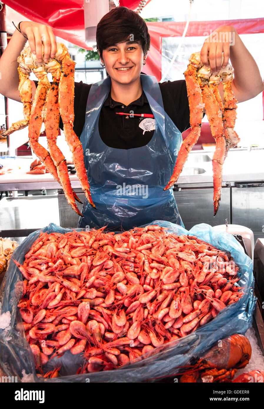 Smiling Fish seller holding up fresh Crab Legs and shrimp. Famous Bergen Fish Market, Bergen, Norway, Hordaland, Scandinavia Stock Photo