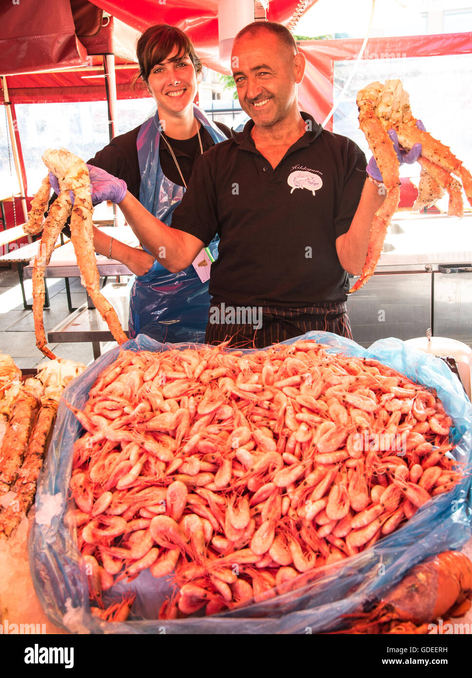 Fish sellers holding up fresh Crab Legs and bushel of shrimp. Famous Bergen Fish Market, Bergen, Norway, Hordaland, Scandinavia Stock Photo