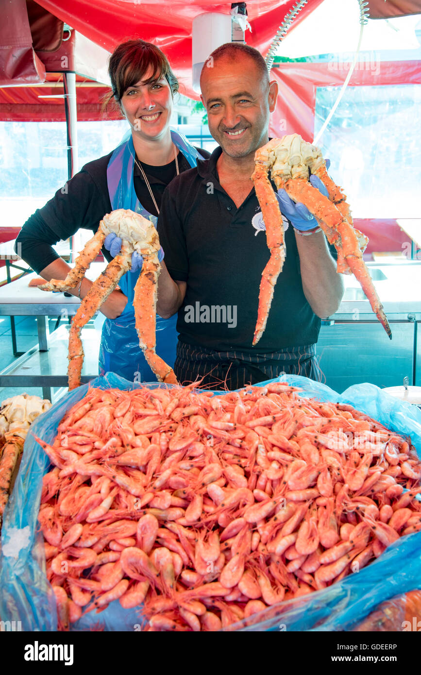 FIsh vendors holding up fresh crab legs and shrimp from the Sea. Bergen's Famous Fish Market, Norway, Hordaland, Scandinavia, Stock Photo