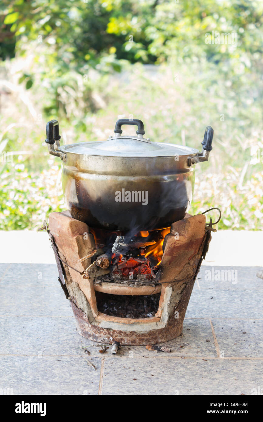 Old aluminium pot on stove with fire and smoke, folk cooking way Stock
