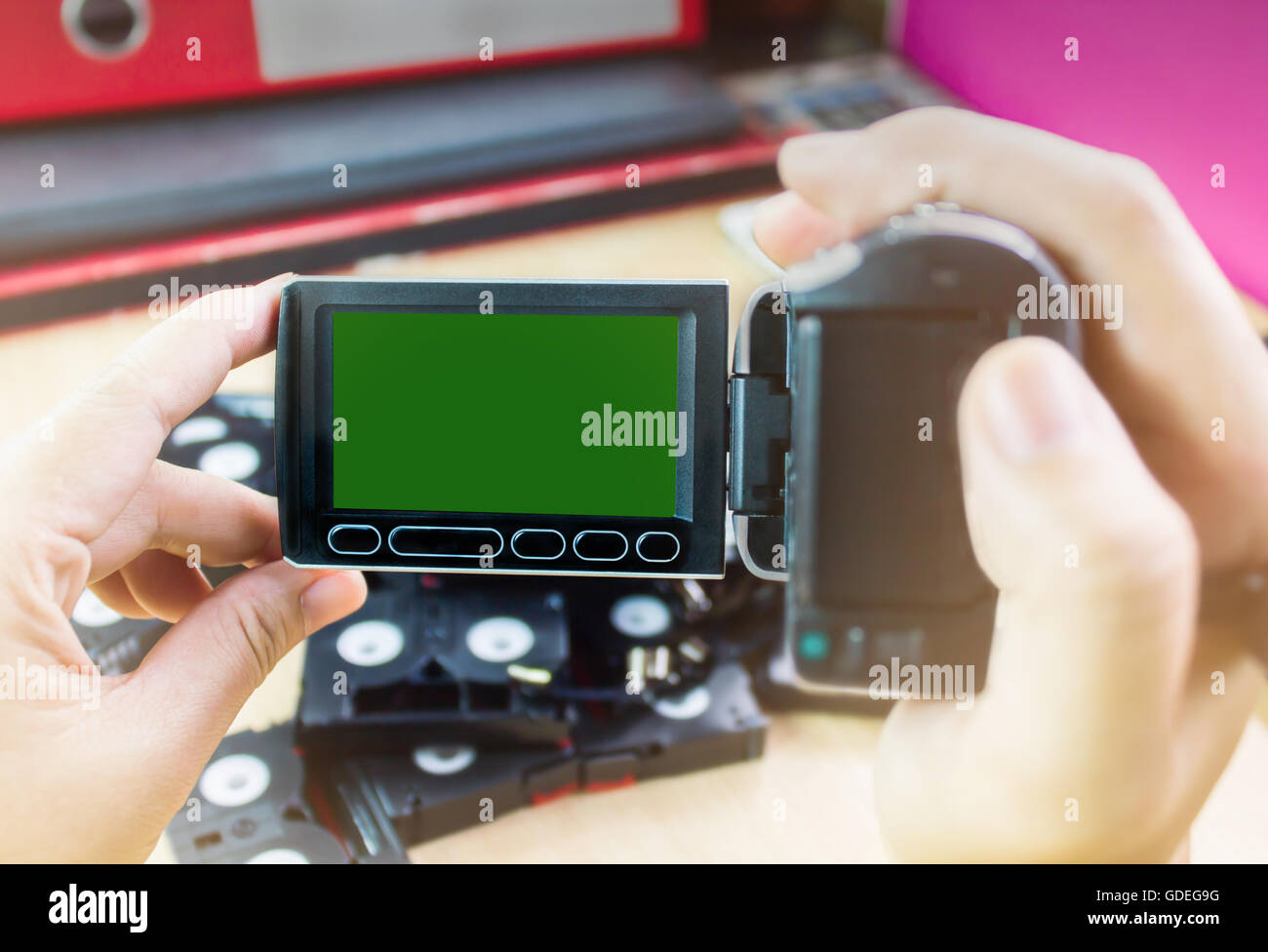 Hand and video camera recording cassette tapes in office background