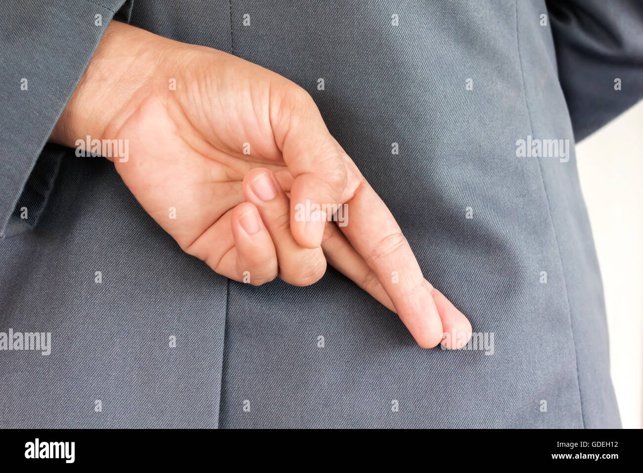 Making lie symbol finger hiden behind people dress in business suit Stock  Photo - Alamy