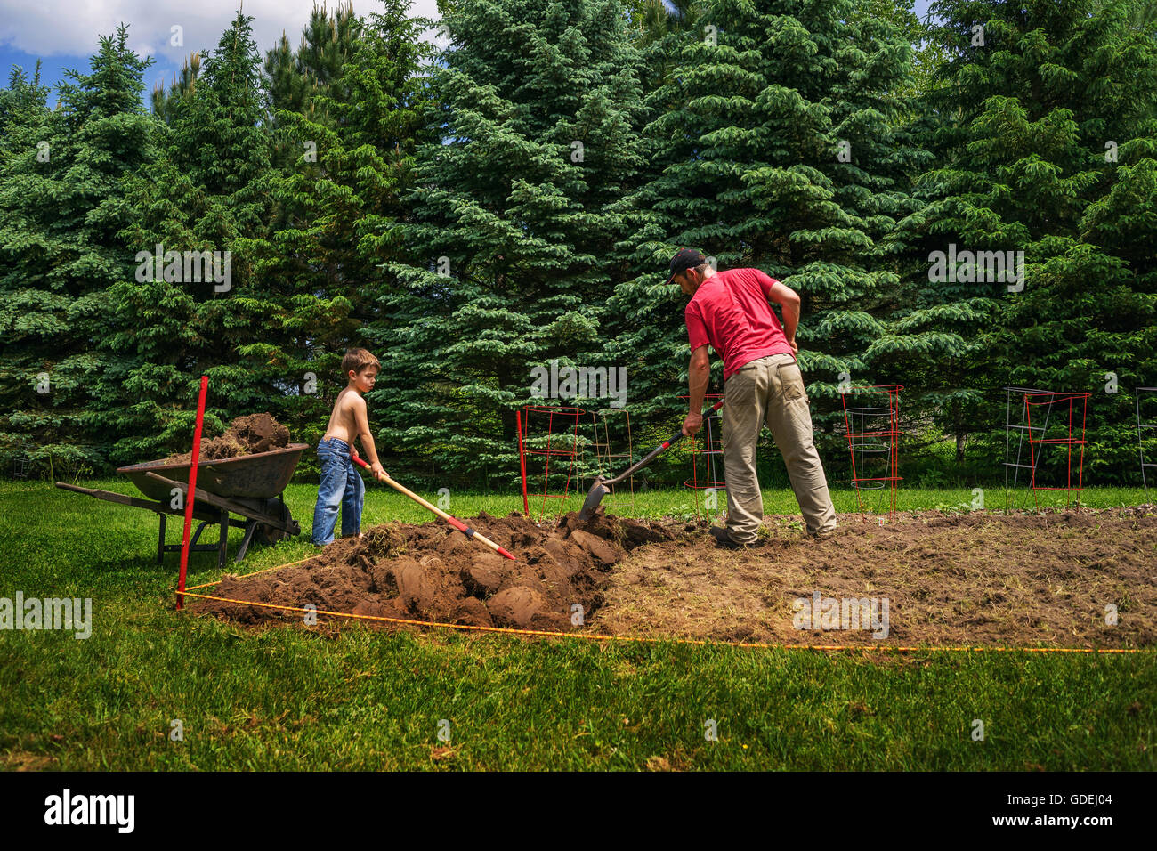 Father and son digging soil in garden Stock Photo