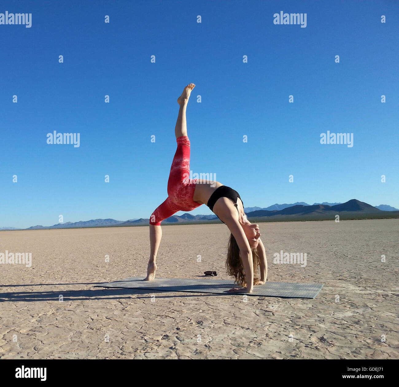 Woman doing a one legged wheel pose in a dry lake, Nevada, United States Stock Photo