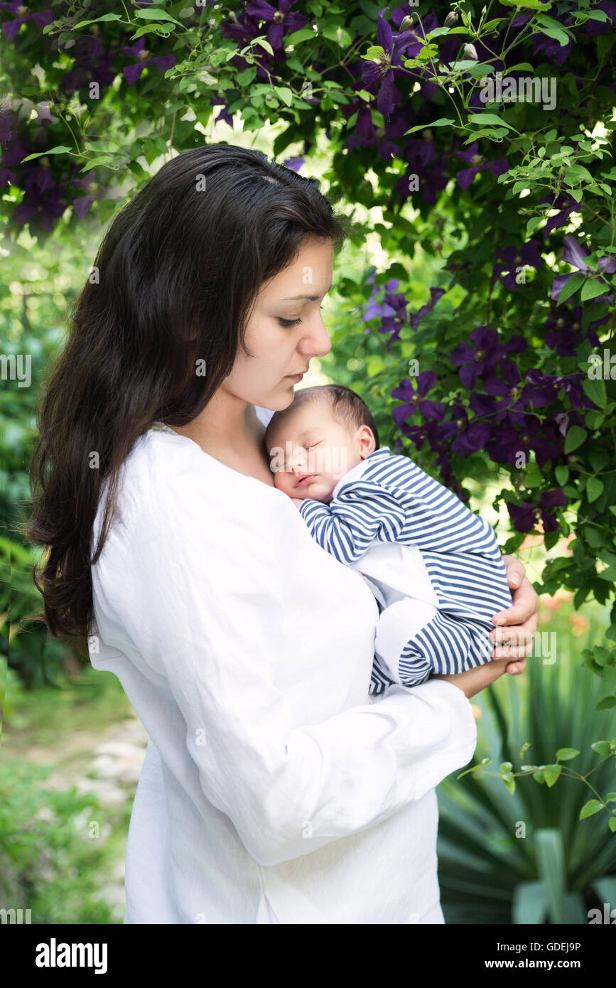Mother holding sleeping baby in garden Stock Photo