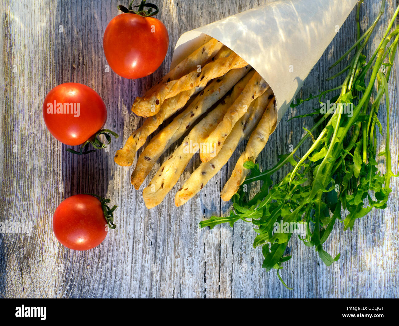 overhead view of bread sticks, fresh rucola leaves and tomatoes Stock Photo