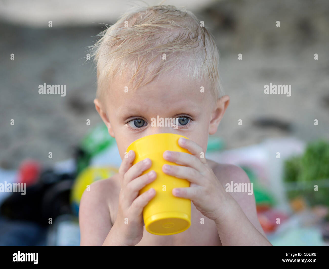 Boy drinking water from plastic cup on beach Stock Photo
