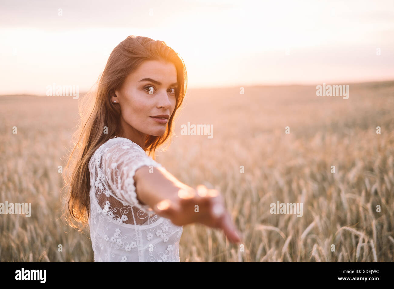 Woman standing in wheat field with outstretched arm Stock Photo