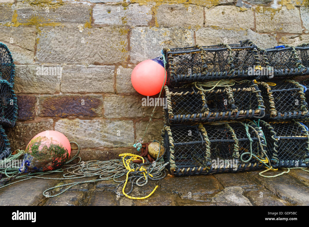 Lobster pots (creels) on an old stone harbour wall in Scotland. Stock Photo