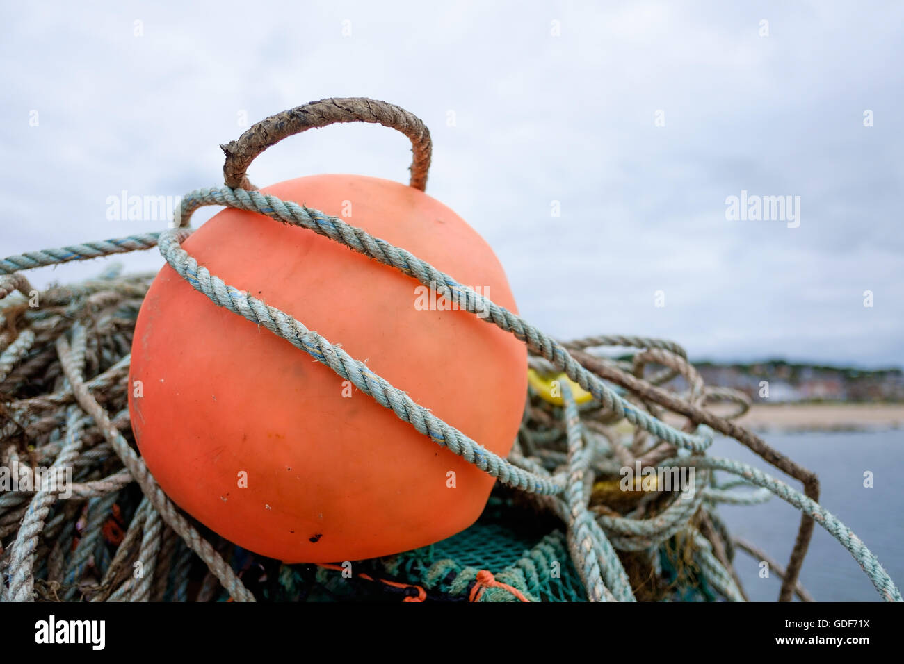 A big orange marker buoy and ropes at a fishing harbour. Stock Photo