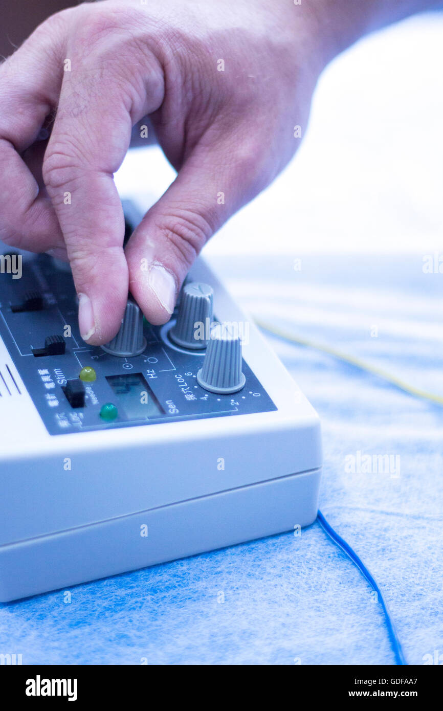 Dry needling electroacupunture machine connected to needles used by acupunturist on patient in