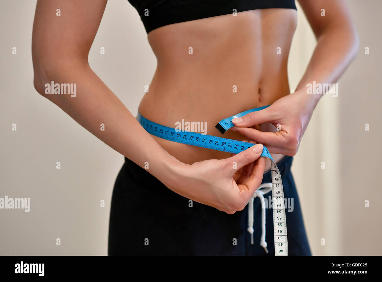 Young woman measures belly circumference with tape measure Stock Photo