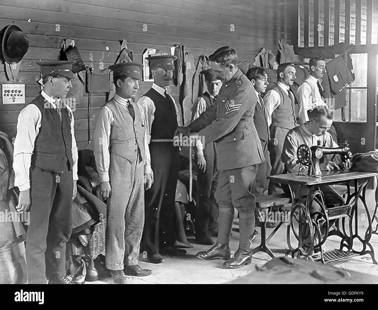 FIRST WORLD WAR  A Sergent measures recruits to the British Army  for  their uniforms. Small adjustments are made by the man at the sewing machine. Official War office photo by Horace Nicholls about 1916 Stock Photo
