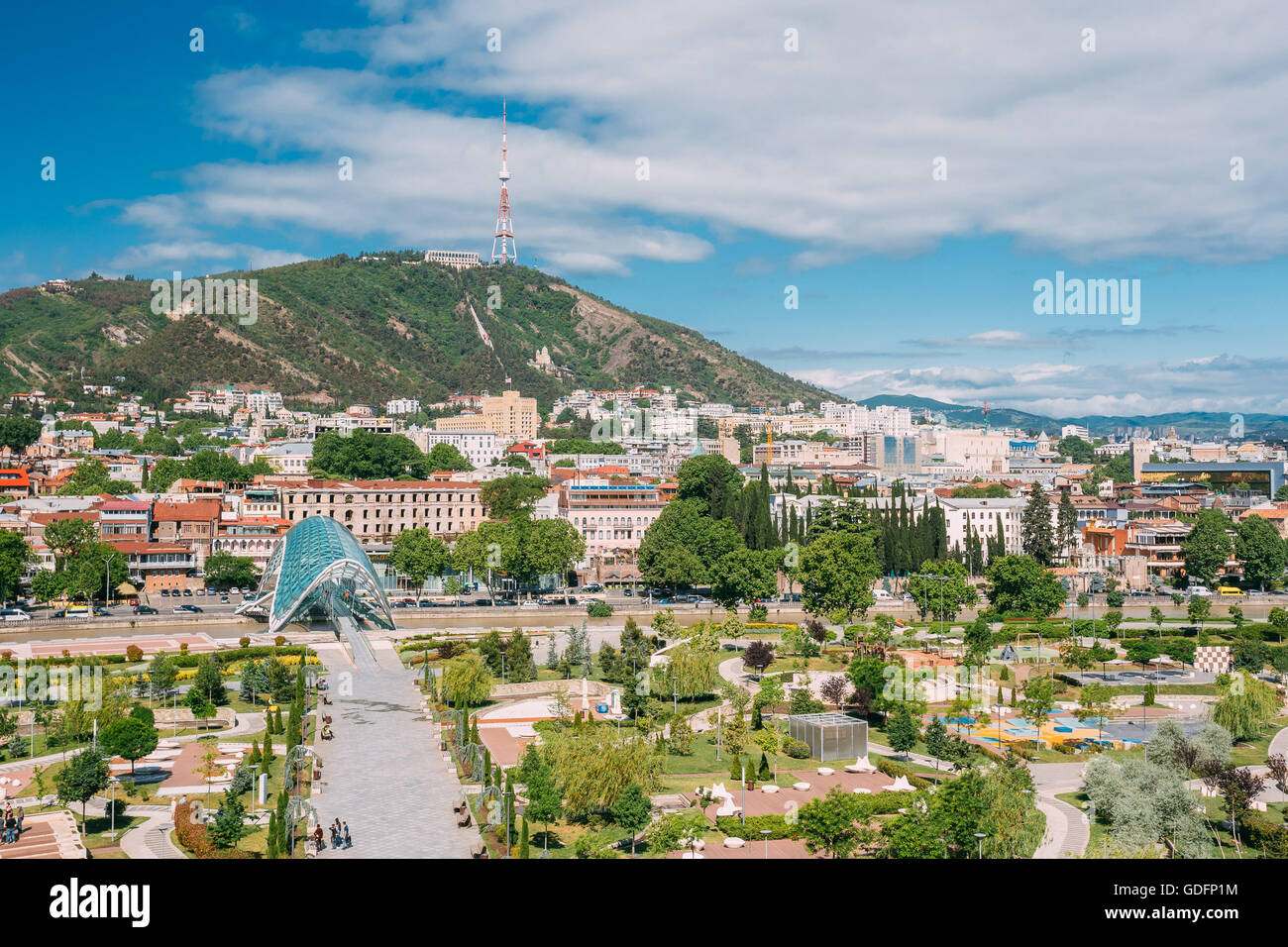 Scenic View Of Park Rike In Tbilisi, Georgia. In Background Is Visible Pedestrian Bridge Of Peace Over The Kura River, Mount Mta Stock Photo