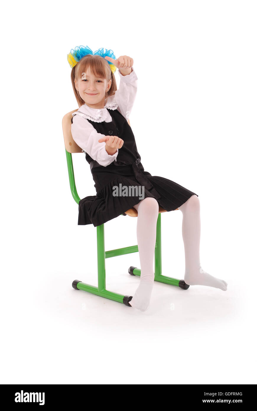 Schoolgirl sitting on the chair showing thumb isolated on white background Stock Photo