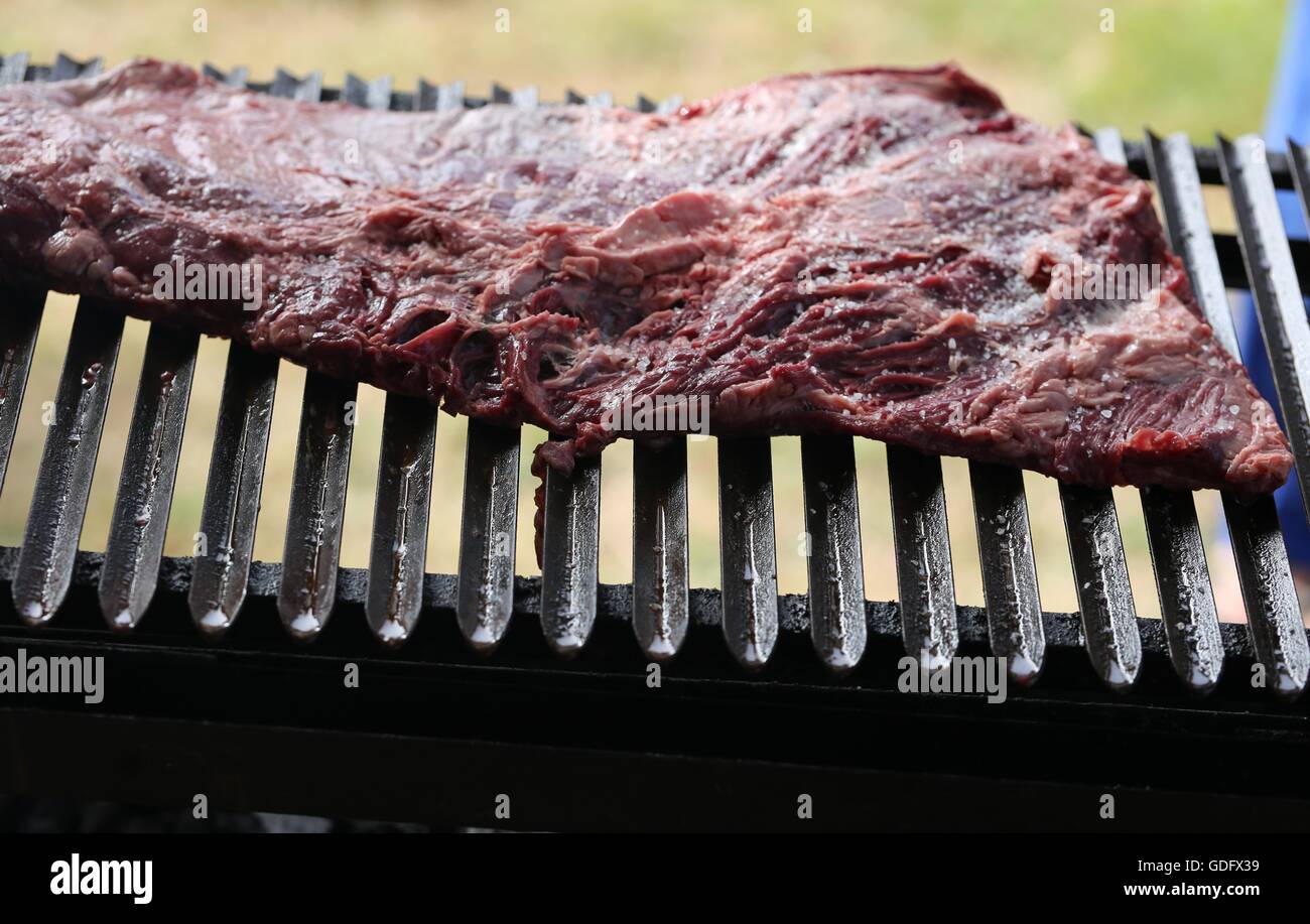 Raw Beef on the Grill. Sinta, Raw meat, raw flesh. Red meat on the grill. Rare sinta, fresh salted asado at the beginning of the holiday picnic meal. Stock Photo
