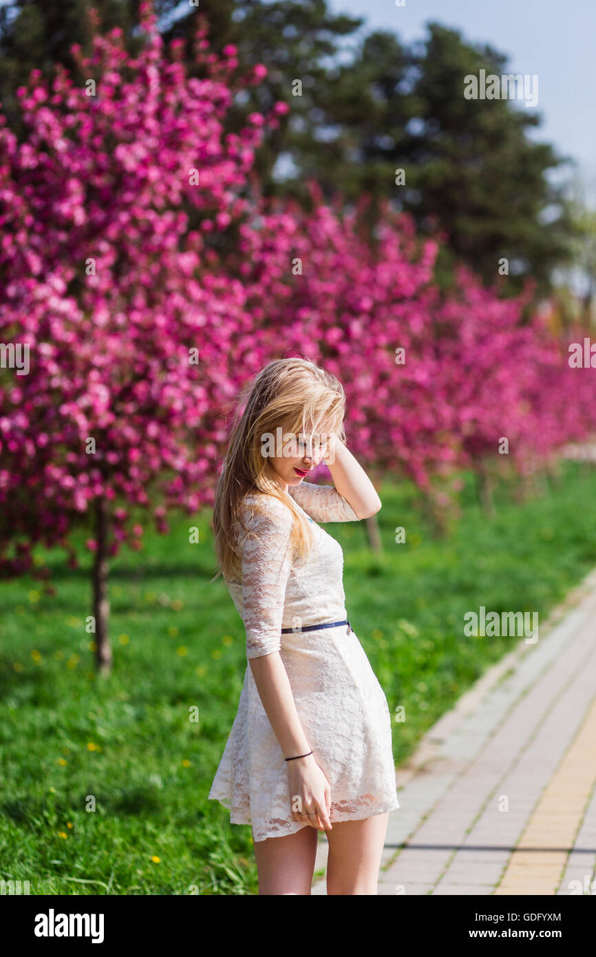 Beautiful blonde girl with long wavy curls in a white dress walk in the ...