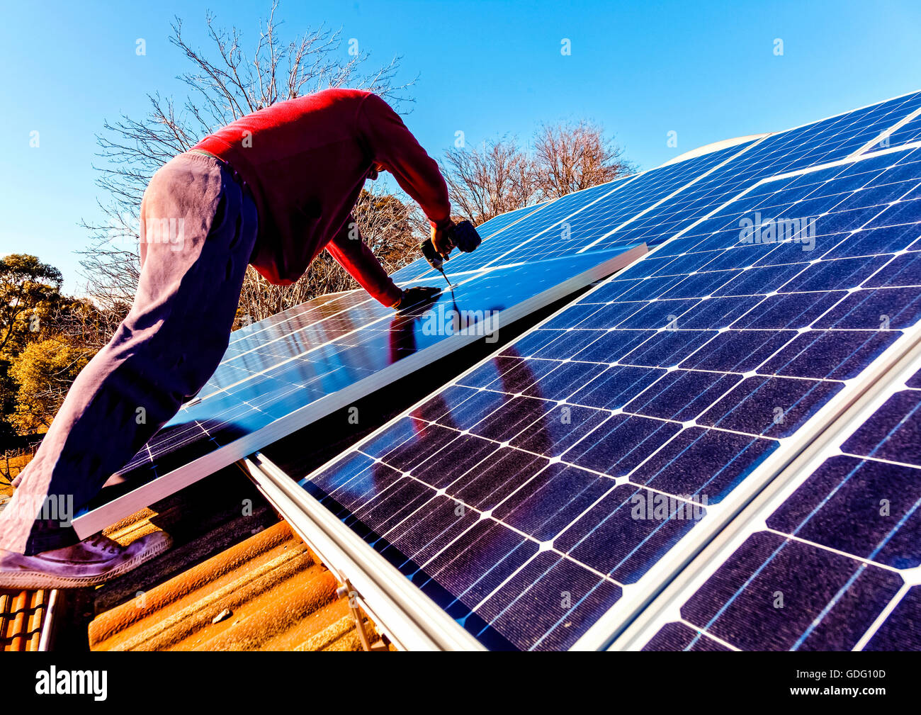 Workman installing solar panels on house roof Stock Photo Alamy