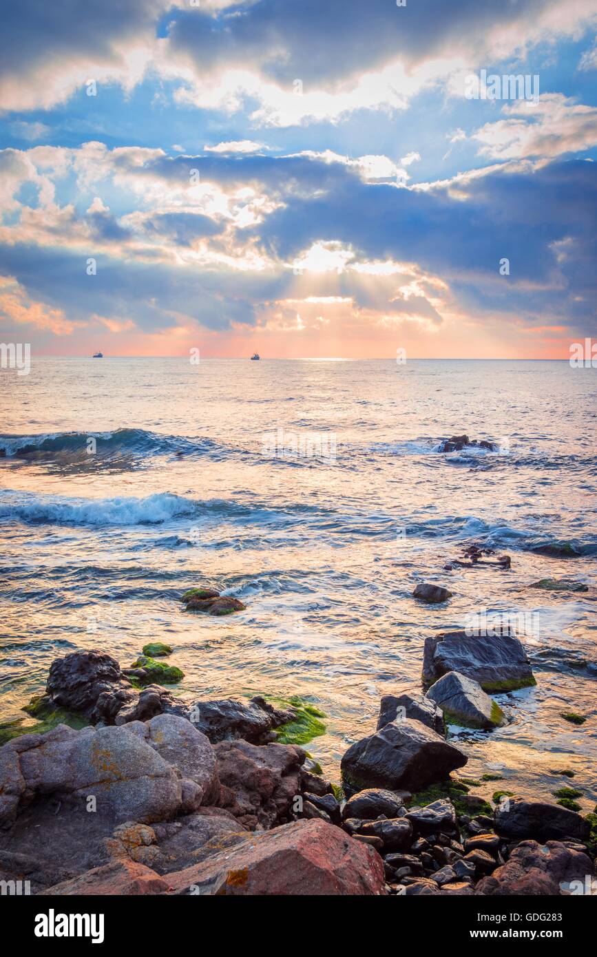 Sunrise over a rocky beach. Colorful clouds reflecting in the sea Stock ...