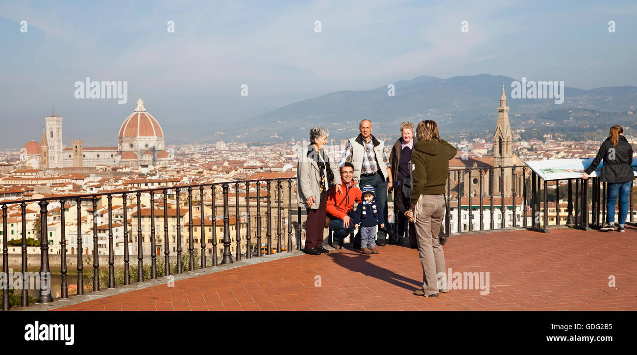 A family of tourists posing for photos on the Piazzale Michelangelo, while another looks at the interpretative board. Stock Photo