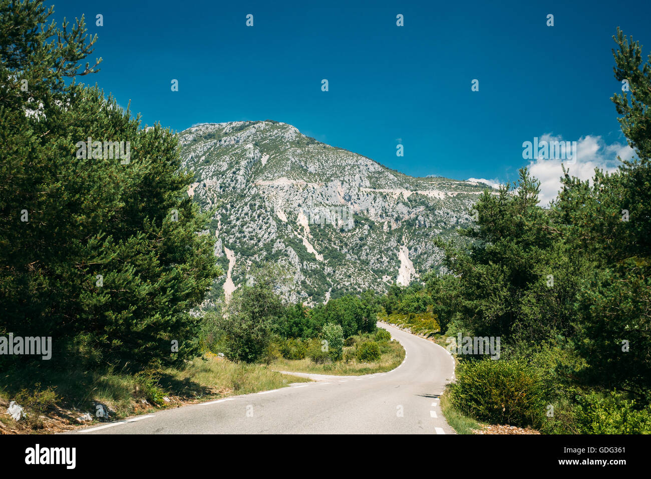 Beautiful asphalt mountain road under sunny blue sky. Travel trip in Europe. Stock Photo