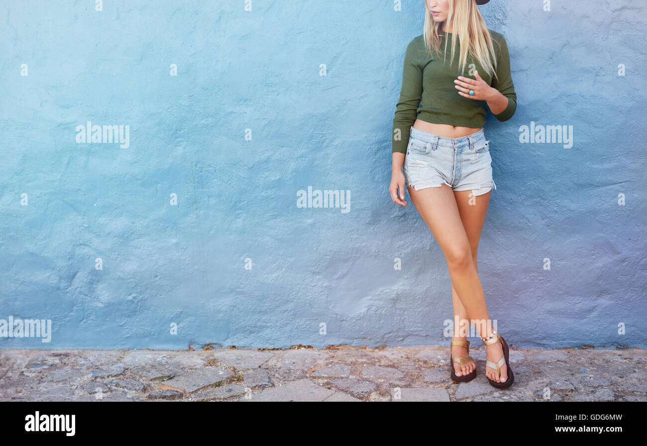 Cropped shot of stylish female model standing against blue wall. Young caucasian woman with copy space. Stock Photo