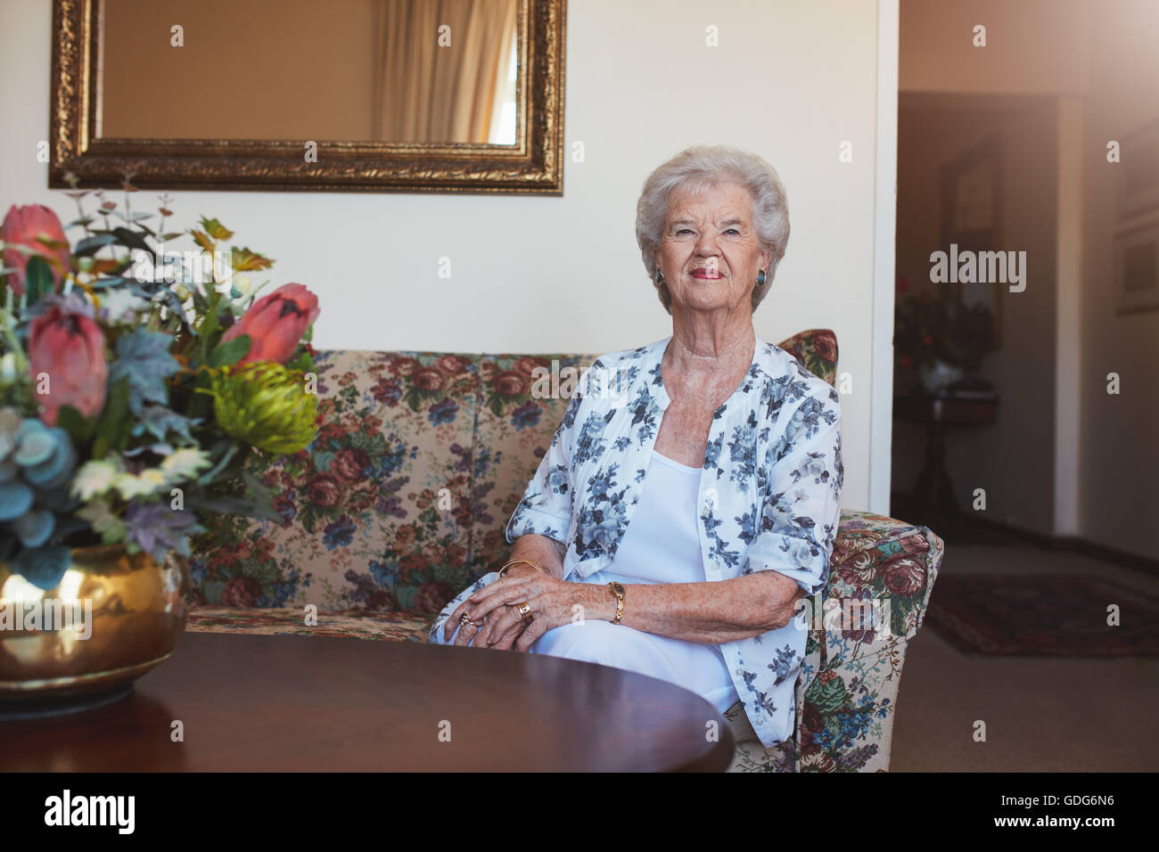 Indoor shot of beautiful senior woman sitting on a couch at old age home. Stock Photo