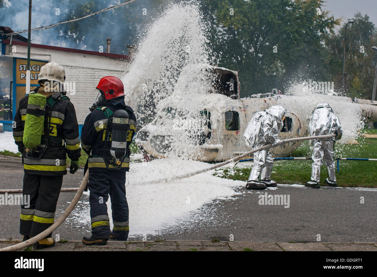 Polish firemen covering foam over the wreck of a helicopter during exercise Stock Photo