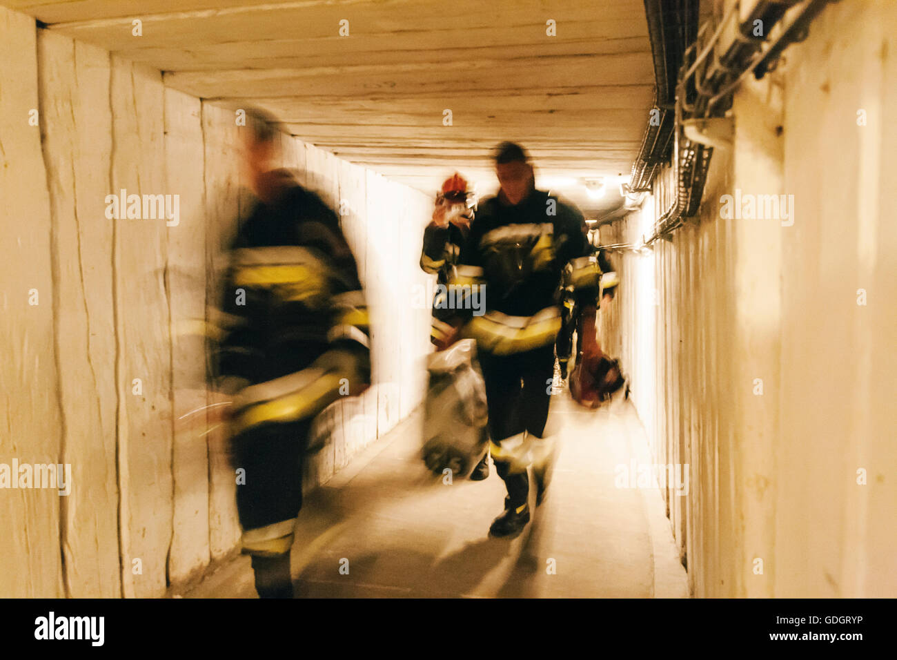 Three blurred tired Polish firefighters walking mine tunnel Stock Photo