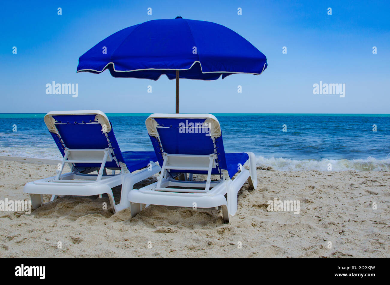 lounge chairs on beach against a clear blue sky Stock Photo