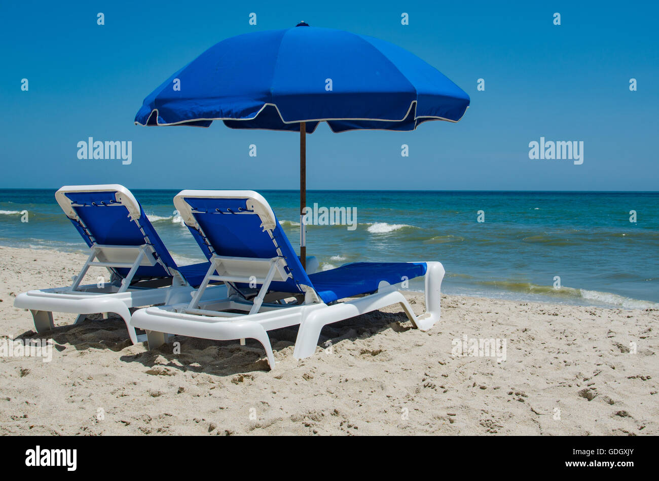 lounge chairs on beach against a clear blue sky Stock Photo