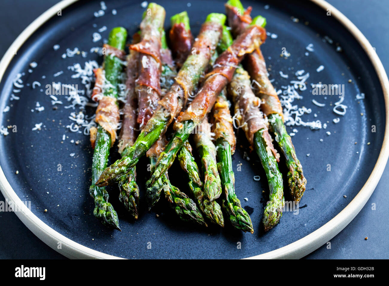 Grilled asparagus wrapped in Parma ham with parmesan, sage and thyme Stock Photo