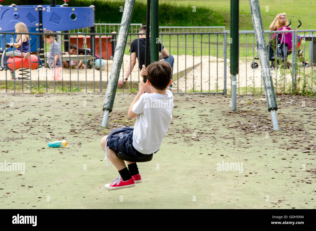 A young boy rides down a zip wire in a children's playground in Prospect Park, Reading, Stock Photo
