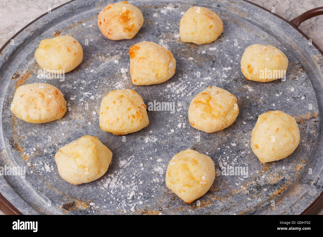 Cooking brazilian snack cheese bread (pao de queijo) on oven-tray. Selective focus Stock Photo
