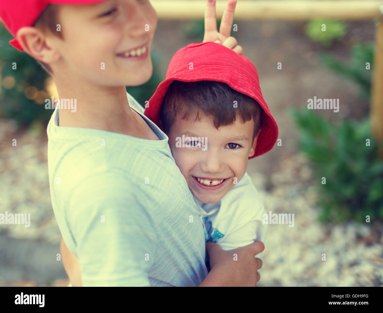 Happy carefree little boy showing donkey ear to younger brother, outdoor, summer holiday Stock Photo