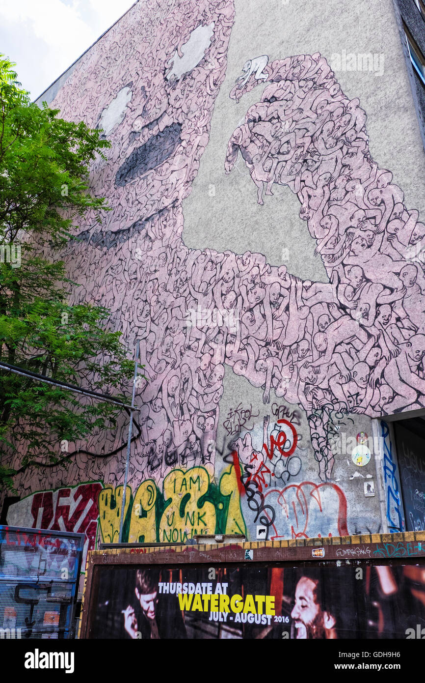 Pink Man by street artist, Blu, Writhing mass of many little people with open mouth to eat a small man, Kreuzberg, Berlin Stock Photo