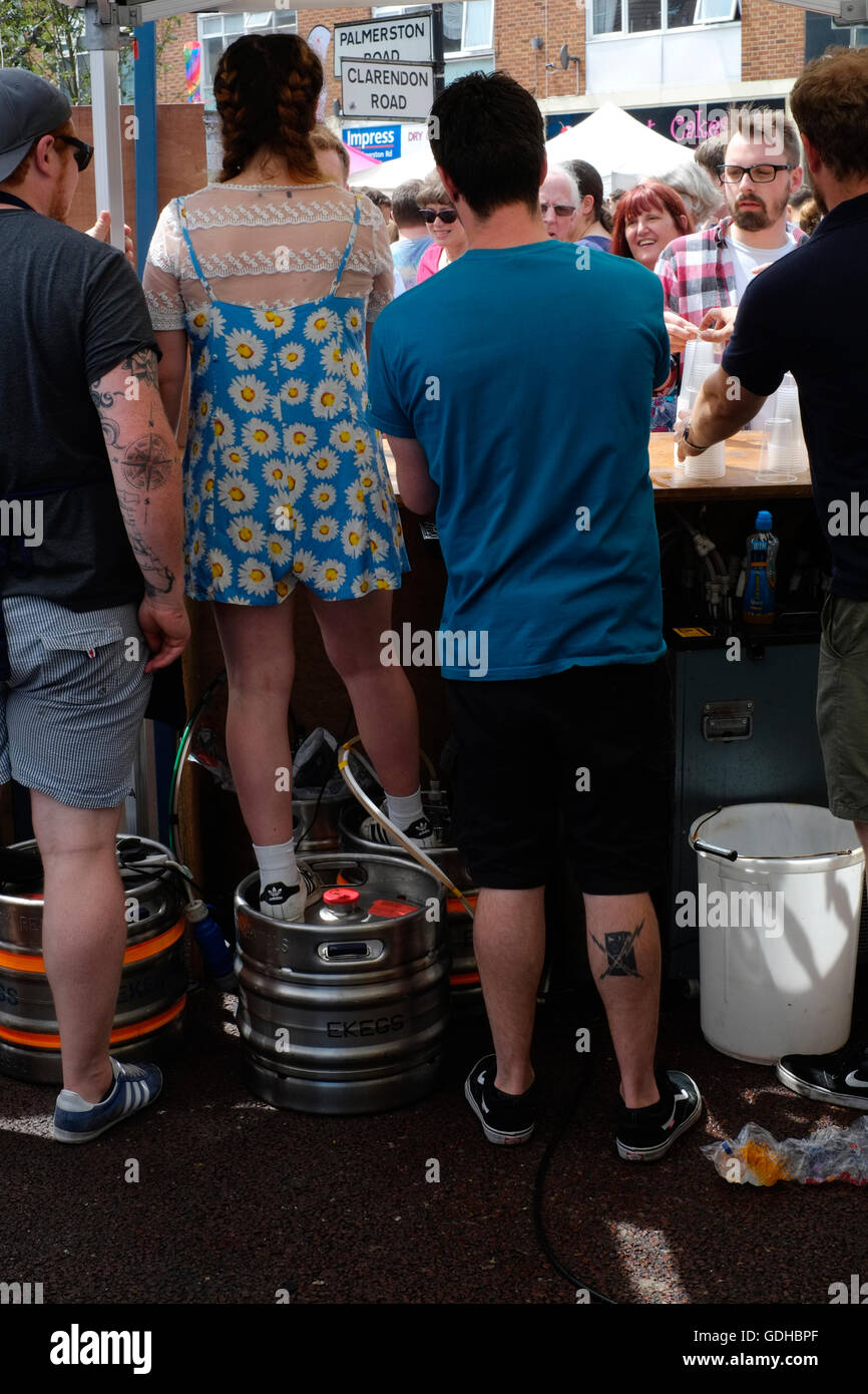 a short barmaid standing on a beer barrel to serve customers at a street bar in southsea uk Stock Photo